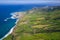 Aerial view of the coastline on Sao Miguel Island, with town buildings, green farmland and volcanic mountains, Azores, Portugal