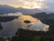 Aerial view of the colorful forest and Lake Bled with a small island with a church. Sunrise in Slovenia in the fall. Castle, aeria