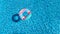 Aerial view of colorful inflatable ring donut toy in swimming pool water from above, family vacation concept