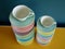 Aerial view of colorful stacked vintage tea and coffee cups on yellow table against petrol background.