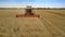 Aerial view combine gathers wheat harvest in wide field