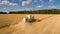 Aerial view combine harvester  harvesting on wheat field, cloudy sky