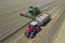 Aerial view of a combine harvester and tractor working in agriculture. Harvest grain field, summer season. Top view dron photo.