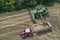 Aerial view of a combine harvester and tractor working in agriculture. Harvest grain field, summer season. Top view dron photo.