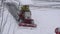 Aerial view of compact tractor with snow plowing equipment cleaning city sidewalk