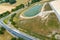 Aerial view of the confluence of two country roads next to a new development with a rain retention basin