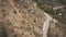 Aerial view, construction an asphalt road on mountain ridge. Excavator digs ground on hill. Nature