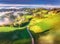 Aerial view of country road in green alpine meadows at sunrise