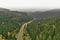 Aerial view of a country road through a valley in the Harz along the Innerste next to slopes densely covered with coniferous