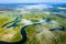 Aerial view on curved river through white clouds. River on green meadow from above. Mist river