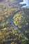 Aerial view of curving road among trees in autumn color in northern Minnesota on sunlit evening