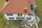 Aerial view on damaged red single house roof after strong wind or explosion. Hole in the rooftop and floor. Rubble on the ground