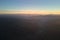 Aerial view of dark mountain hills at sunset. Hazy peaks and misty valleys in evening