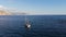 Aerial view Daytime panoramic scenic view of drifting sailing yacht on water, bay surrounded by mountains. Panning