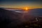 Aerial view of Delphi, Greece, the Gulf of Corinth, orange color of clouds, mountainside with layered hills beyond with