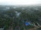 Aerial view of a dense foggy palm forest with several buildings