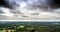 Aerial view of a dense wooded area in Germany, which is crossed by a road at the edge of a city, with dramatic sky