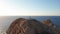 Aerial view of a desolated lighthouse in the middle of a desert island in the ocean, sea with curved road. Rocky shore