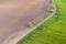 Aerial view, dirt road divides green and brown field