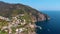 Aerial view from distance of Riomaggiore Village. Houses on the edge of the cliffs. bay with boats. plantation of grapes and olive