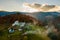 Aerial view of distant village with small shepherd houses on wide hill meadows between autumn forest trees in Ukrainian Carpathian