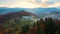 Aerial view of distant village with small shepherd houses on wide hill meadows between autumn forest trees in Ukrainian Carpathian