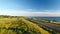 Aerial view of driving black car on the road along the cliff near the sea in summer at sunset.