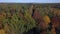 Aerial view of a drone ascending in an autumn forest. Fall landscape with red, yellow and green foliage on a sunny