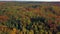 Aerial view of a drone descending in an autumn forest. Fall landscape with red, yellow and green foliage on a sunny