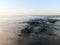 Aerial view of drone flight above clouds at dawn with fog.