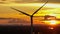 Aerial view drone orbit around silhouette wind turbines farm at sunset, renewable electric energy