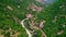 Aerial view of drone over mountain road and curves going through forest landscape