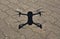 Aerial view on drone shadow on concrete ground, Quadcopter during landing procedure in sunny day