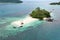 Aerial view drone shot of peoples on a tropical small island with trees, rocky and white sand beaches in the middle of the ocean.