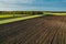 Aerial view with a drone of a spring wavy agricultural countryside landscape with plowed and unplowed fields and trees