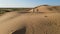 Aerial view from a drone. Woman in a long leopard dress walks along a high dune in the desert with grass in summer in