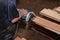 Aerial view of electric circular saw is being cut a piece of wood against hands of senior carpenter in carpentry workshop.