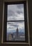 Aerial view of the Empire State Building framed in window on top of Rockfeller Center skyscraper