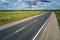 Aerial view of empty intercity road between green agricultural fields. Top view from drone of highway roadway