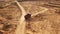 Aerial view of the empty large red truck moving on a sandy track for the sand in desert or dunes. Beautiful view from