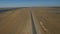 Aerial view on empty road in the desert or field in the middle of nowhere. Cinematic footage of 2 lanes motorway.