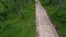 Aerial view of enduro motorcyclist rides on motorcycle on road in wild jungle.