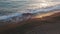 Aerial view of excited young woman walking in foamy Mediterranean sea waves on beach at sunset. Happy Caucasian slim