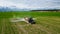 Aerial view, Farmer on a tractor with a sprayer makes fertilizer for young vegetables