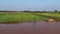 Aerial view of farmer walking along a paddy in Asia, with muddy water in foreground