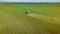 Aerial view of farming tractor cultivates soil in agricultural crops at field