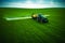 Aerial view of farming tractor plowing and spraying on field