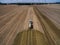 aerial view of a farming tractor with a trailer fertilizes a freshly plowed agriculural field with manure