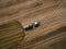 Aerial view of a farming tractor with a trailer fertilizes a freshly plowed agriculural field with manure