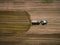 Aerial view of a farming tractor with a trailer fertilizes a freshly plowed agriculural field with manure